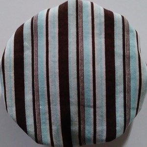 May include: A brown and blue striped fabric with a slightly oval shape.