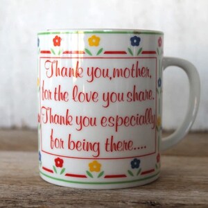 K&ouml;nnte beinhalten: Wei&szlig;e Keramiktasse mit einem roten, gr&uuml;nen, blauen und gelben Blumendesign. Die Tasse hat einen Henkel und sagt "Danke, Mutter, f&uuml;r die Liebe, die du teilst. Danke besonders daf&uuml;r, dass du da bist..."