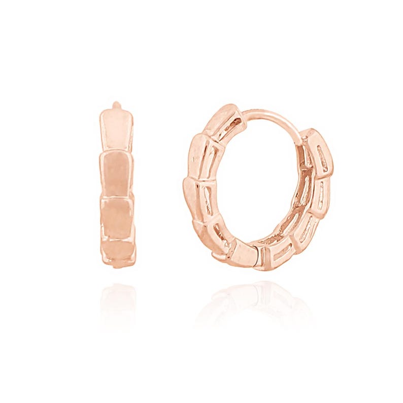 May include: A pair of rose gold hoop earrings. Each earring features a segmented design, with rectangular links creating a textured appearance. The earrings are displayed against a white background, highlighting their metallic sheen.