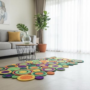 Puede incluir: Una colorida alfombra hecha a mano compuesta por círculos de varios tamaños en tonos verdes, morados, naranjas y amarillos. La alfombra está colocada sobre un suelo claro frente a un sofá gris y una ventana con cortinas blancas. El diseño de la alfombra añade un toque lúdico a la habitación.