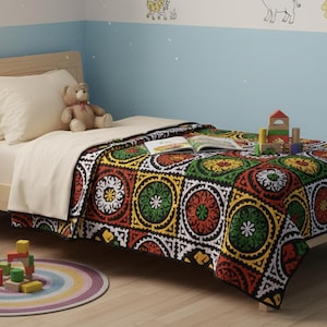 May include: A child's bedroom with a wooden bed, a colorful patterned quilt, and a teddy bear. A book and wooden blocks are on the bed. A round rug with rainbow stripes and more blocks are on the floor. The walls are light blue.