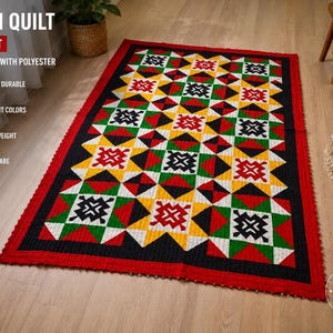 May include: A rectangular Ralli quilt measuring 4x7 feet, crafted from a cotton and polyester blend. The quilt features a geometric pattern in vibrant red, yellow, green, black, and white, finished with a solid red border and stitched texture.