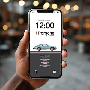 May include: A smartphone displaying a Porsche 911 Turbo 930 graphic. The screen shows the time, date, and car specifications, including engine specs and production years. The car is light blue with a side stripe.