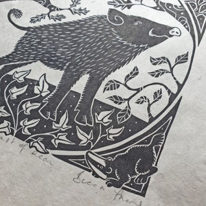A snippet of Becca Thorne's Beast Of Dean linocut print, showing the bottom right corner of the print. A badger is framed in a triangular shape, looking in and up towards a wild boar. The boar looks proud, standing amongst woodland foliage.