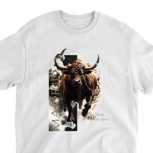 May include: White t-shirt featuring a brown bull in mid-stride with large horns. The bull is set against a black and white vertical design with the word "MADRID" and the text "Ventas del Espíritu Santo".
