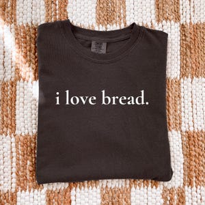 Simple. Honest. Relatable.
This “I Love Bread” Comfort Colors t-shirt is made for anyone who believes bread deserves more appreciation. Featuring clean, minimalist text and a soft, lived-in feel, this tee is the perfect blend of humor and everyday comfort.