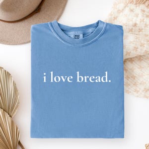 Simple. Honest. Relatable.
This “I Love Bread” Comfort Colors t-shirt is made for anyone who believes bread deserves more appreciation. Featuring clean, minimalist text and a soft, lived-in feel, this tee is the perfect blend of humor and everyday comfort.