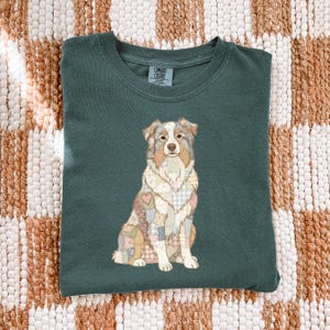 May include: Dark teal Comfort Colors t-shirt featuring a seated dog illustration with a patchwork design. The dog has a heart on its chest. The shirt is made of soft material.