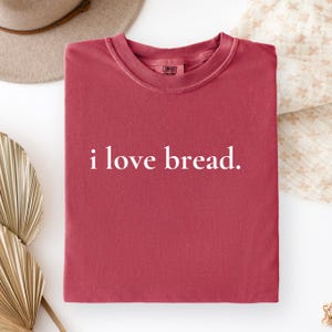 Simple. Honest. Relatable.
This “I Love Bread” Comfort Colors t-shirt is made for anyone who believes bread deserves more appreciation. Featuring clean, minimalist text and a soft, lived-in feel, this tee is the perfect blend of humor and everyday comfort.