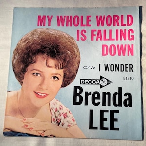 May include: Vintage vinyl record cover featuring Brenda Lee. The cover has a light blue background with the text "MY WHOLE WORLD IS FALLING DOWN" in pink. The singer's portrait is on the left, with the text "I WONDER" and "DECCA" below.