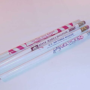 May include: Four pencils with various designs and text. One pencil has pink and white diagonal stripes. The other pencils are white with text that includes "STATE BANK WAUPUN", "U.S. AIR FORCE MUSEUM", and other text.