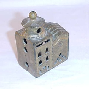 May include: A vintage metal piggy bank shaped like a building with a domed roof. The bank has multiple slots for coins and is painted in a bronze color.
