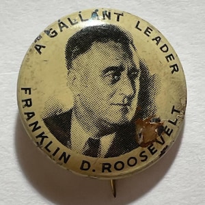 May include: Vintage pin featuring a black and white portrait of Franklin D. Roosevelt. The pin has the text "A Gallant Leader" and "Franklin D. Roosevelt" around the image. The pin is circular with a safety pin on the back.