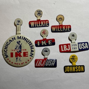 May include: A collection of vintage political campaign pins and buttons. The items include pins with the names "Willkie", "Ike", and "Johnson", and a large button that says "Michigan Minuteman Vote for Ike".