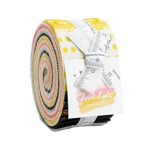 May include: A rolled bundle of fabric strips in a variety of colors, including yellow, pink, black, and white. The fabric is secured with a white ribbon and a tag that reads "first light". The fabric is likely for quilting or other sewing projects.