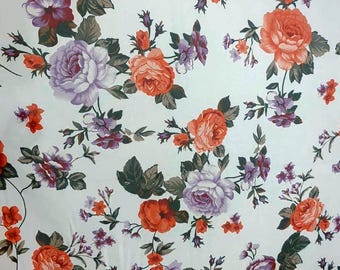 May include: White fabric with a repeating floral pattern. The design features large orange and purple roses, smaller red and purple flowers, and green leaves. The flowers are scattered across the white background.