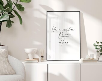 May include: A framed print with the text "Your custom Quote Here" in elegant script. The black frame surrounds a white background. The print is displayed on a white cabinet, alongside decorative items like a white bowl, books, and a small diffuser.