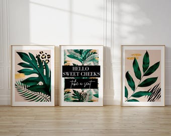 May include: Three framed prints with a tropical theme. The center print features a green and gold tropical leaf design with the text "HELLO SWEET CHEEKS take a seat". The left and right prints feature a similar green and gold tropical leaf design.
