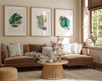 May include: A brown sectional sofa with three throw pillows and a blanket, a wooden coffee table, and three framed prints with abstract tropical leaf designs in shades of green, gold, and white.