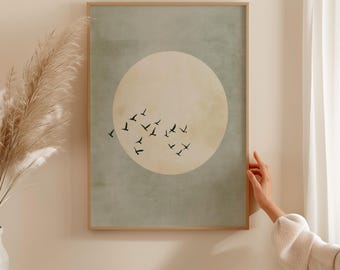 May include: A framed print with a minimalist design featuring a large, off-white circle with a flock of black birds flying around it. The background is a muted green colour.