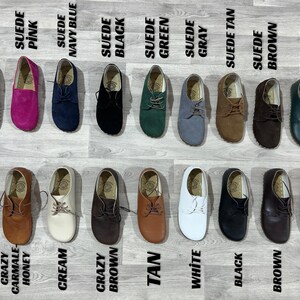 Puede incluir: Una colecci&oacute;n de zapatos de ante y cuero en varios colores, incluyendo azul marino, rosa, negro, verde, gris, marr&oacute;n, marr&oacute;n y naranja. Los zapatos se muestran sobre una superficie gris claro, con los nombres de los colores.