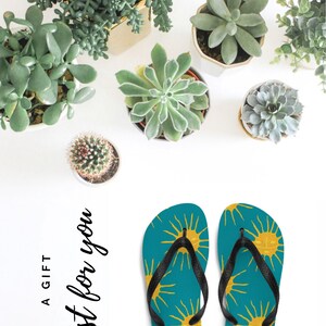 May include: A pair of teal blue flip flops with a black strap. The flip flops have a pattern of yellow suns with a face on them. The text 'A GIFT just for you' is written in black cursive on a white background. summer havaianas