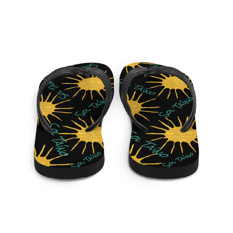 Black havaianas or flipflops with Taino sun symbols and the words sol Taino in blue colors. Chancletas con sol Taino Arte original por Artista Puertorriquena.   #latinartwork #chancletas #buylatinartwork #blackflipflops