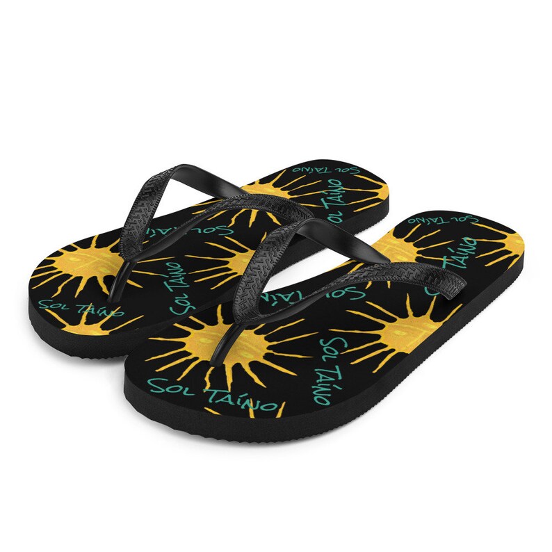 Black flipflops with Taino sun symbols and the words sol Taino in blue colors .Chancletas con sol Taino Arte original por Artista Puertorriquena.   #latinartwork #chancletas #buylatinartwork #blackflipflops |  summer havaianas