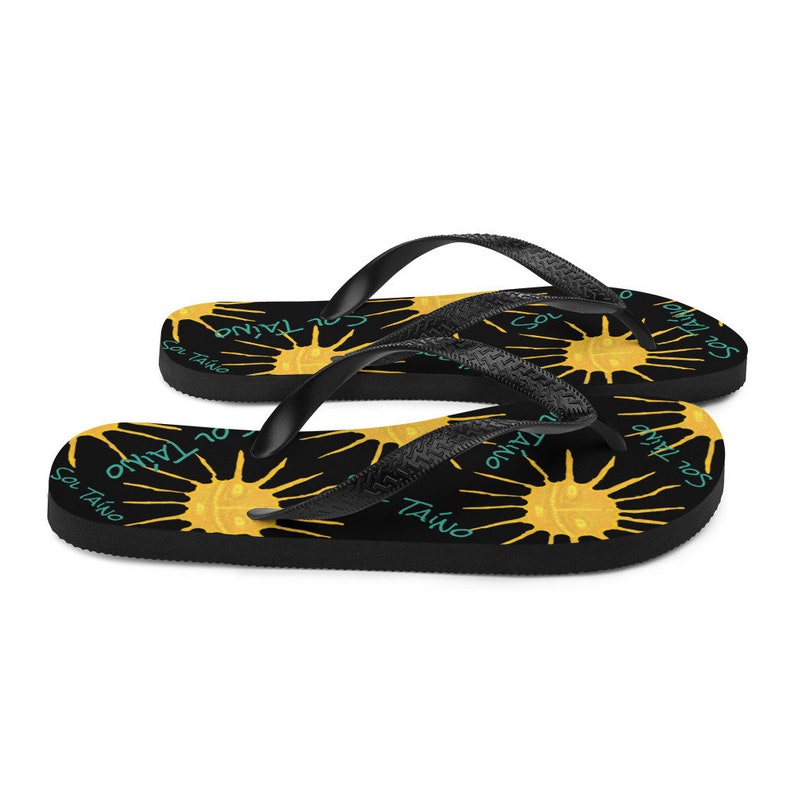 Black flipflops with Taino sun symbols and the words sol Taino in blue colors .Chancletas con sol Taino Arte original por Artista Puertorriquena.   #latinartwork #chancletas #buylatinartwork #blackflipflops