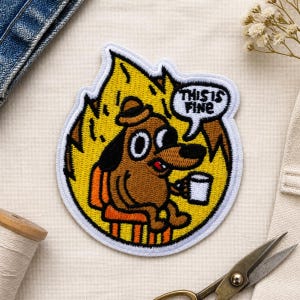Könnte beinhalten: Ein gestickter Aufnäher mit einem braunen Hund mit Hut, der auf einem orangefarbenen Stuhl inmitten gelber Flammen sitzt. Der Hund hält eine weiße Tasse und eine Sprechblase darüber enthält den schwarzen Text THIS IS FINE. Weißer Rand.