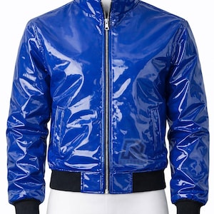 Puede incluir: Una chaqueta azul real brillante con cuello alto y cremallera plateada de longitud completa. La prenda presenta puños y dobladillo acanalados en color negro. Un pequeño logotipo tenue con la letra R es visible en la parte inferior derecha.
