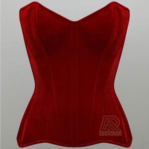 Puede incluir: Un cors&eacute; de terciopelo rojo con una silueta estructurada. Presenta un escote de coraz&oacute;n y costuras verticales. La prenda tiene un logotipo en la esquina inferior derecha.