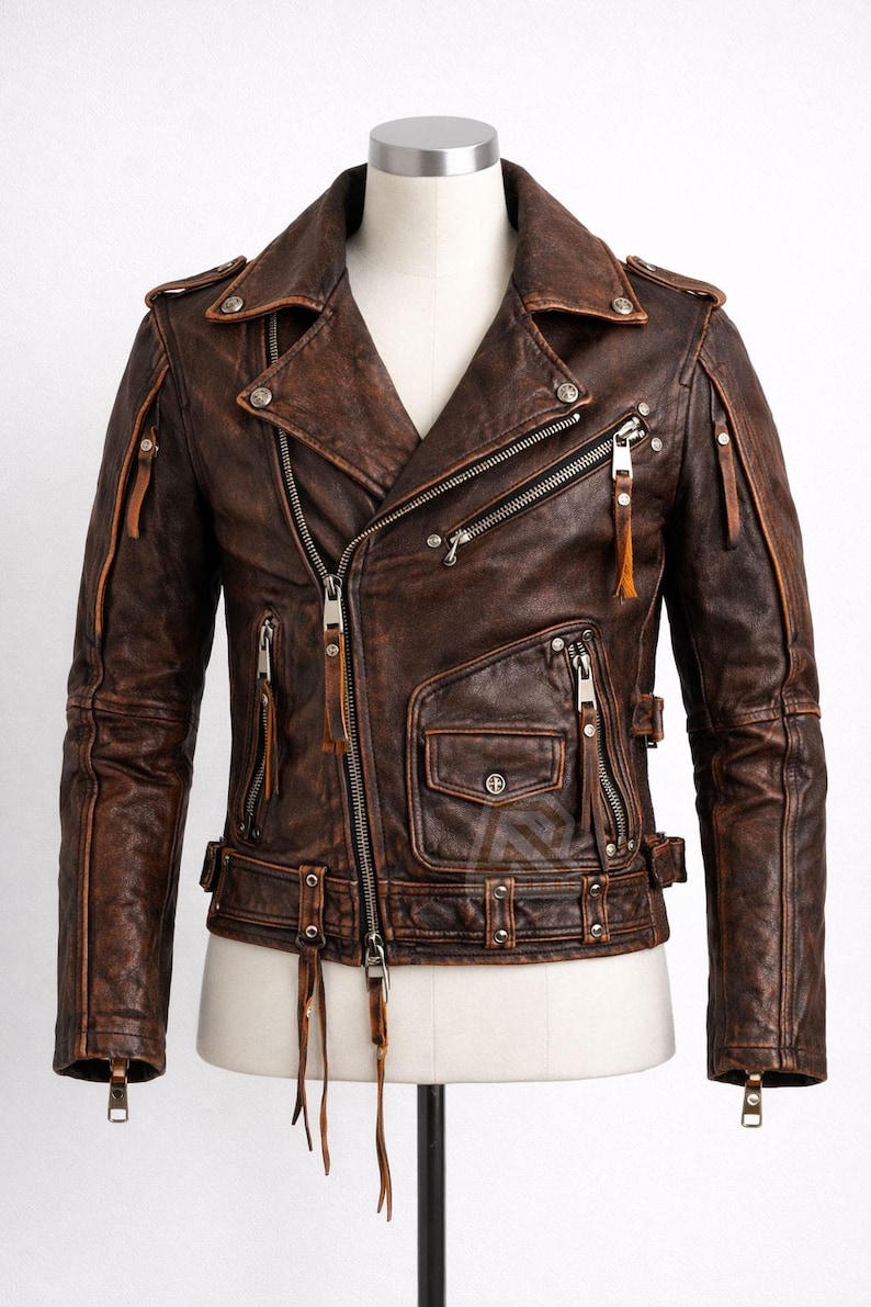 May include: Brown leather jacket with a distressed finish. Features multiple zippered pockets, a notched collar, and a front zipper closure. Includes silver-tone hardware and decorative leather tassels. The jacket is displayed on a mannequin.