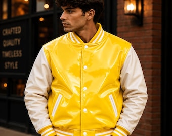 May include: A glossy yellow varsity jacket with white sleeves, a ribbed collar, cuffs, and hem featuring white stripes. The jacket has a front button closure with white buttons and two slanted side pockets with white trim, worn over blue jeans.