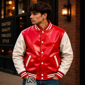 May include: A glossy red varsity jacket with cream-coloured sleeves. The jacket features a snap-button front closure, white and red striped ribbed cuffs, a matching striped collar, and two side pockets with white trim. The material has a shiny finish.