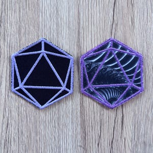 May include: Two hexagonal embroidered patches featuring a twenty-sided die design. The left patch has a solid black background with light purple stitching. The right patch features a dark, swirling fractal pattern with vibrant purple embroidery.