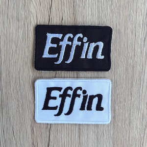May include: Two rectangular embroidered patches. One is black with light blue text that reads "Effin". The other is white with black text that reads "Effin".