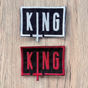 May include: Two rectangular patches with the word "KING" embroidered in a bold font. One patch has white lettering on a black background with a white border. The other has red lettering on a black background with a red border.