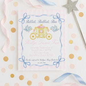 May include: A whimsical invitation with the text "Bibbidi, Bobbidi, Boo" and "Hallye Turns Two". The design features a pink and yellow carriage, blue birds, and a silver star wand. Pink and blue ribbons and confetti surround the invitation.