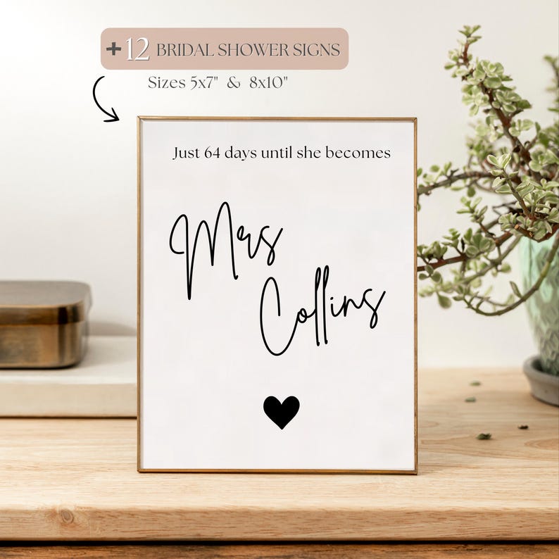 May include: A framed white sign with the text "Just 64 days until she becomes Mrs Collins" in black script, with a black heart below. The sign is in a gold frame. The sign is for bridal showers and comes in 5x7" and 8x10" sizes.