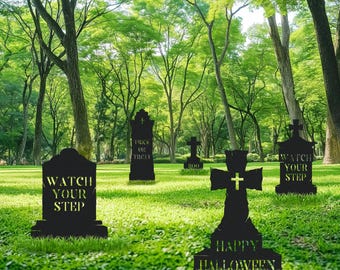 May include: Black Halloween yard decorations in a grassy area. The decorations include tombstones with phrases like "Watch Your Step" and "Trick or Treat", and a cross with "Happy Halloween" text. The background features trees.