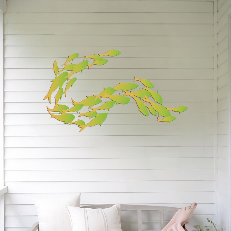 May include: A wall decor featuring a school of green and yellow fish in a curved formation. The fish are made of wood and are mounted on a white wall.