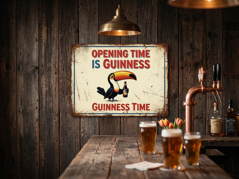 Op de afbeelding: Een vintage metalen bord met de tekst "Opening Time is Guinness, Guinness Time" en een cartoon toekan die een Guinness-fles vasthoudt. Het bord hangt aan een rustieke houten muur, met een bar en bierglazen.