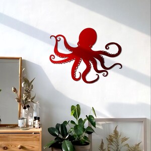May include: Red metal octopus wall decor with eight tentacles. The octopus is mounted on a white wall.