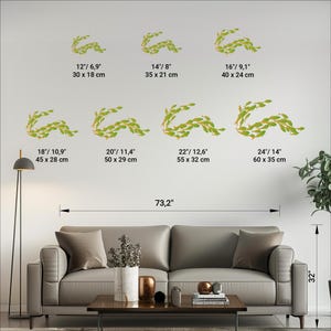 May include: A set of 8 wall decals featuring a leafy garland design in shades of green. The decals are shown in various sizes, ranging from 12 inches to 24 inches in width. The decals are shown on a white wall in a living room setting.