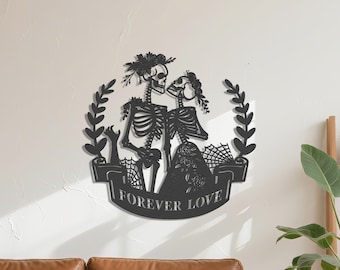 May include: Black metal wall art depicting two skeletons in an embrace, wearing floral crowns, set within a laurel wreath. A banner below reads "FOREVER LOVE". The design includes a spiderweb and floral details, suitable for gothic or Halloween decor.