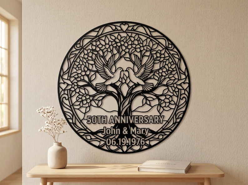 May include: A circular black wall art piece featuring a laser-cut tree design with two doves perched in the branches. The text reads 50TH ANNIVERSARY, John & Mary, and 06.19.1976. The intricate cutout pattern includes leaves and heart shapes.