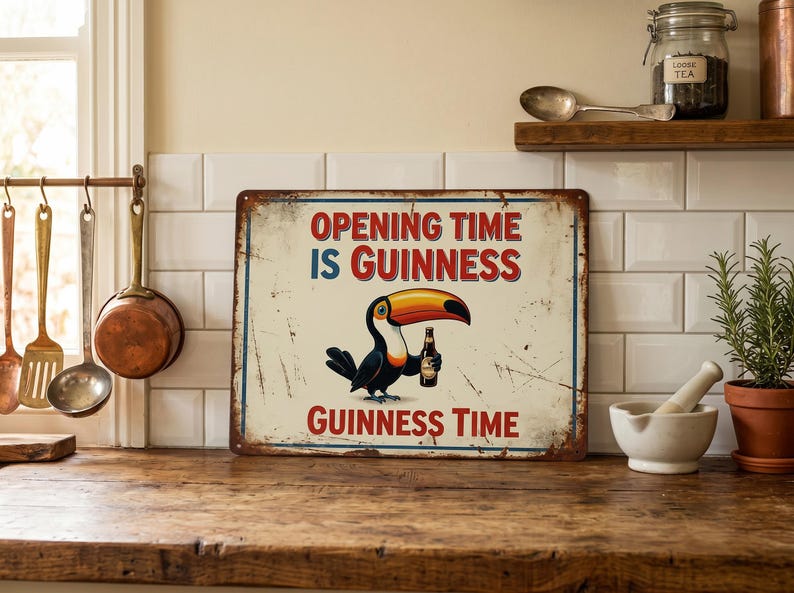 Op de afbeelding: Een metalen bord in vintage stijl met de tekst "OPENING TIME IS GUINNESS" in rood en blauw. Een toekan met een Guinness-fles staat in het midden. Het bord heeft een verweerde, verouderde uitstraling, geschikt voor een bar of keuken.