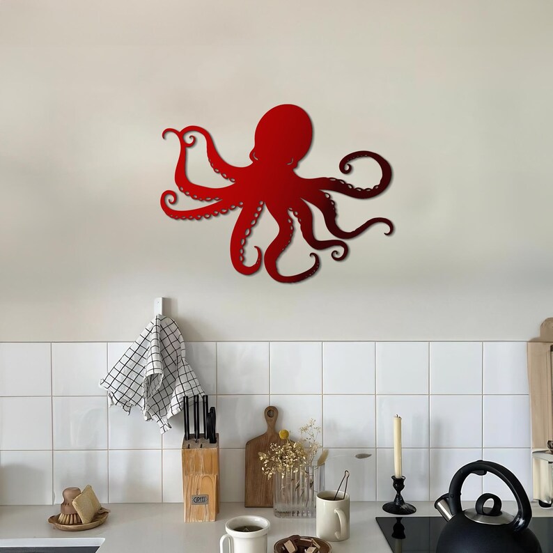 May include: Red metal octopus wall decor with a detailed design. The octopus is mounted on a white tiled wall in a kitchen setting.