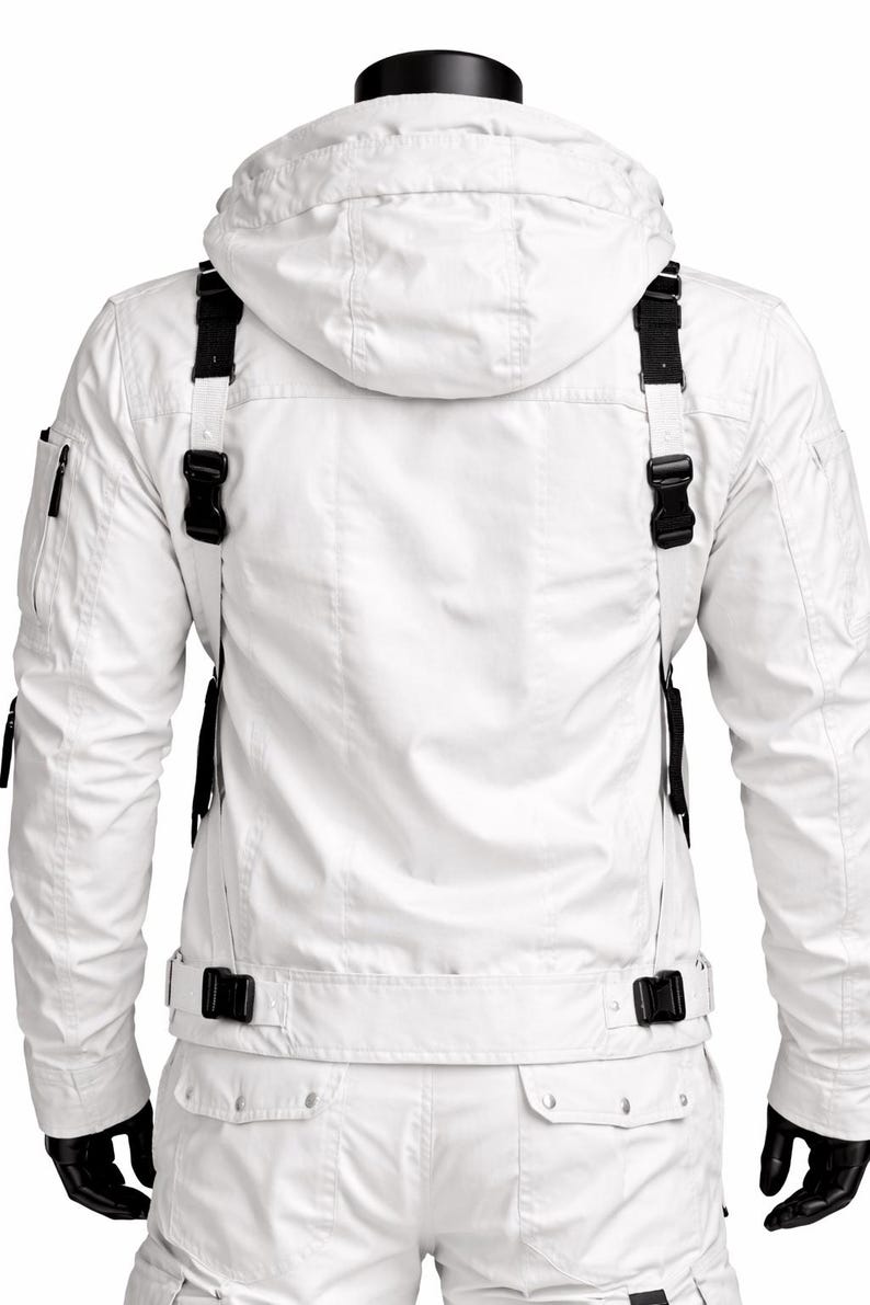 Pu&ograve; includere: Completo giacca e pantaloni bianchi con dettagli neri. La giacca presenta un cappuccio, cinghie nere con fibbie e una tasca con zip. I pantaloni hanno tasche cargo e una cintura con fibbia. Il modello indossa guanti neri.